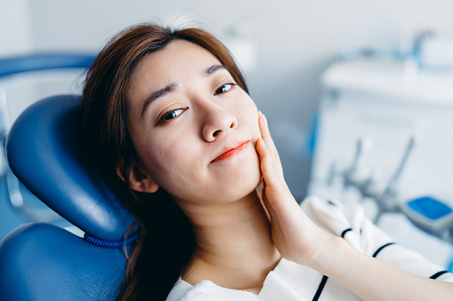A woman with a toothache sitting in a dentist chair